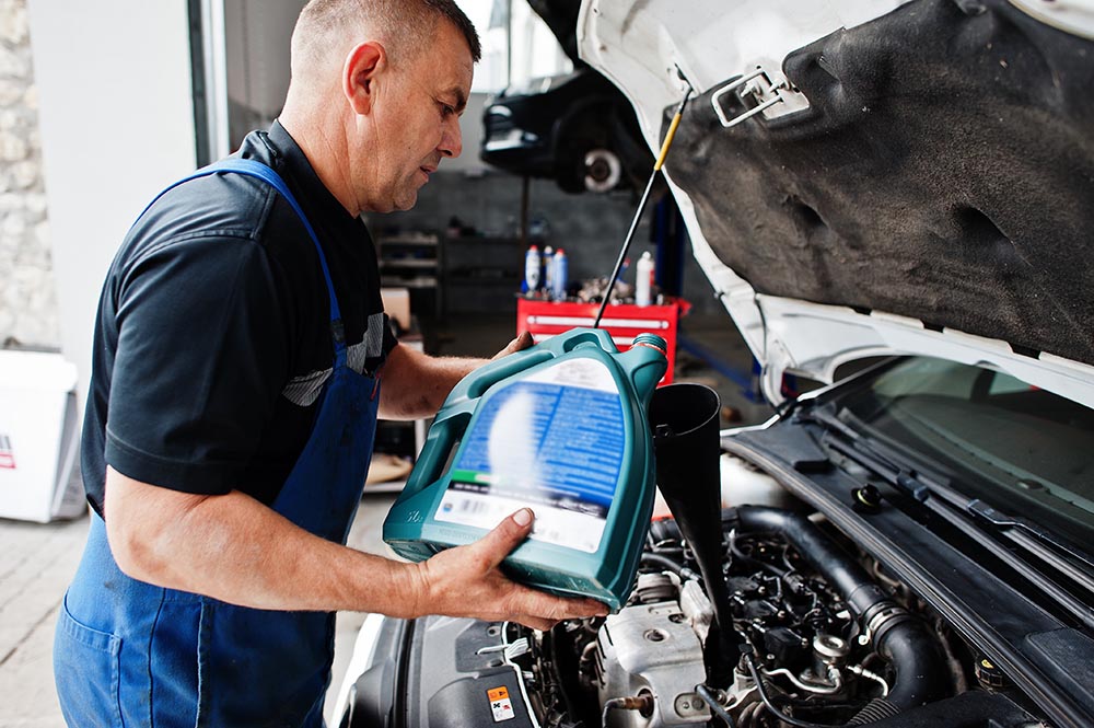 car repair maintenance theme mechanic uniform working auto service pouring new motor oil